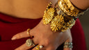 Escravas em filigrana e pulseira em ouro martelado no pulso, sobre vestido vermelho